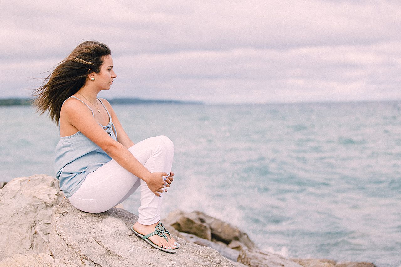 High school senior sitting on a rock near Lake Michigan