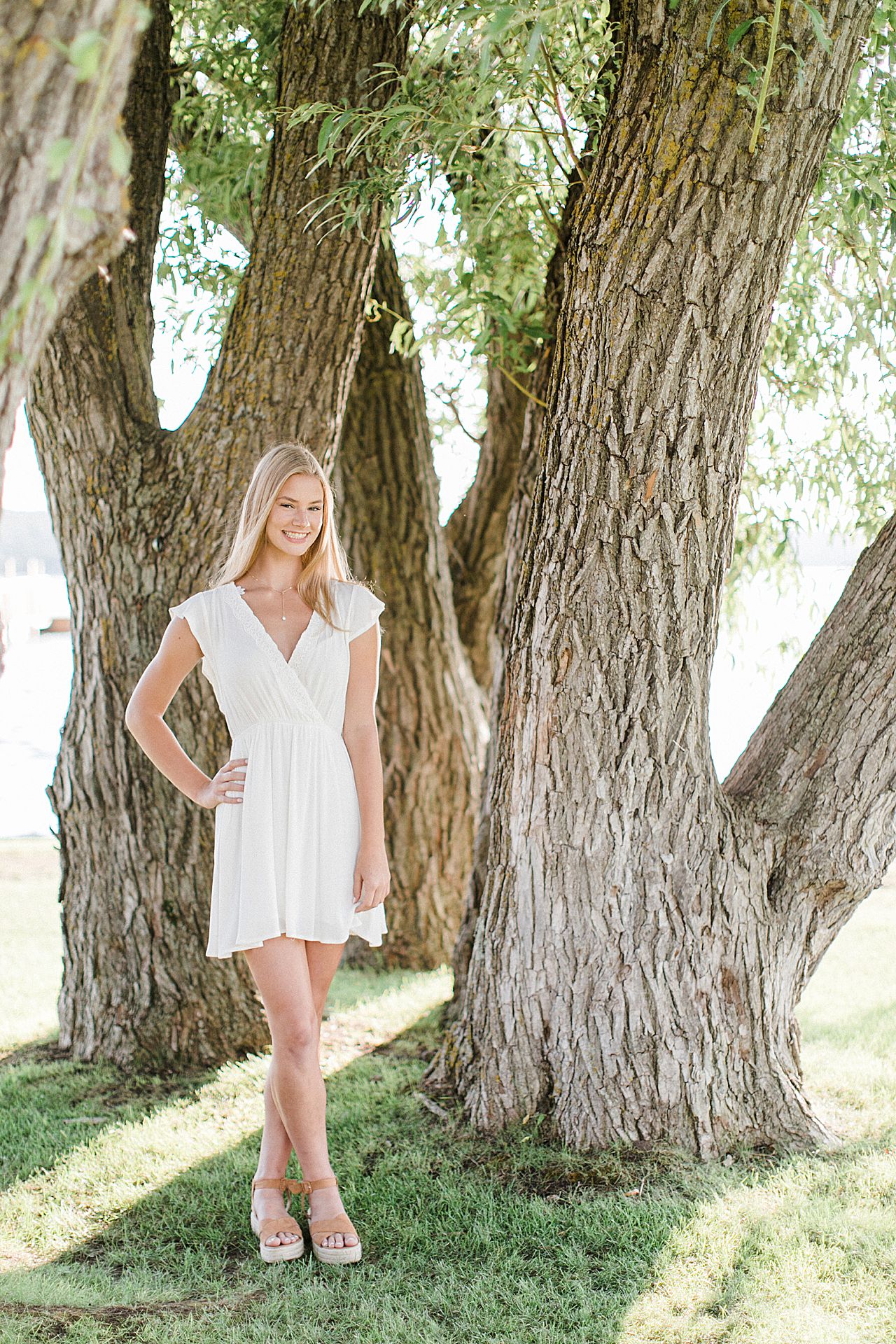 This is a high school senior having portraits by a willow tree in Northern Michigan