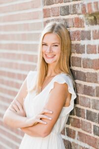 This is a photo of a high school senior girl in downtown Boyne City, Michigan leaning against a brick wall