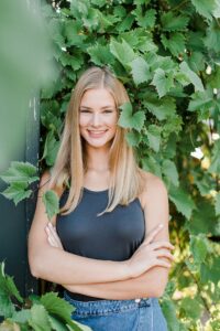 This is a portrait in downtown Boyne City, Michigan of a high school senior looking at the camera and smiling with her arm crossed