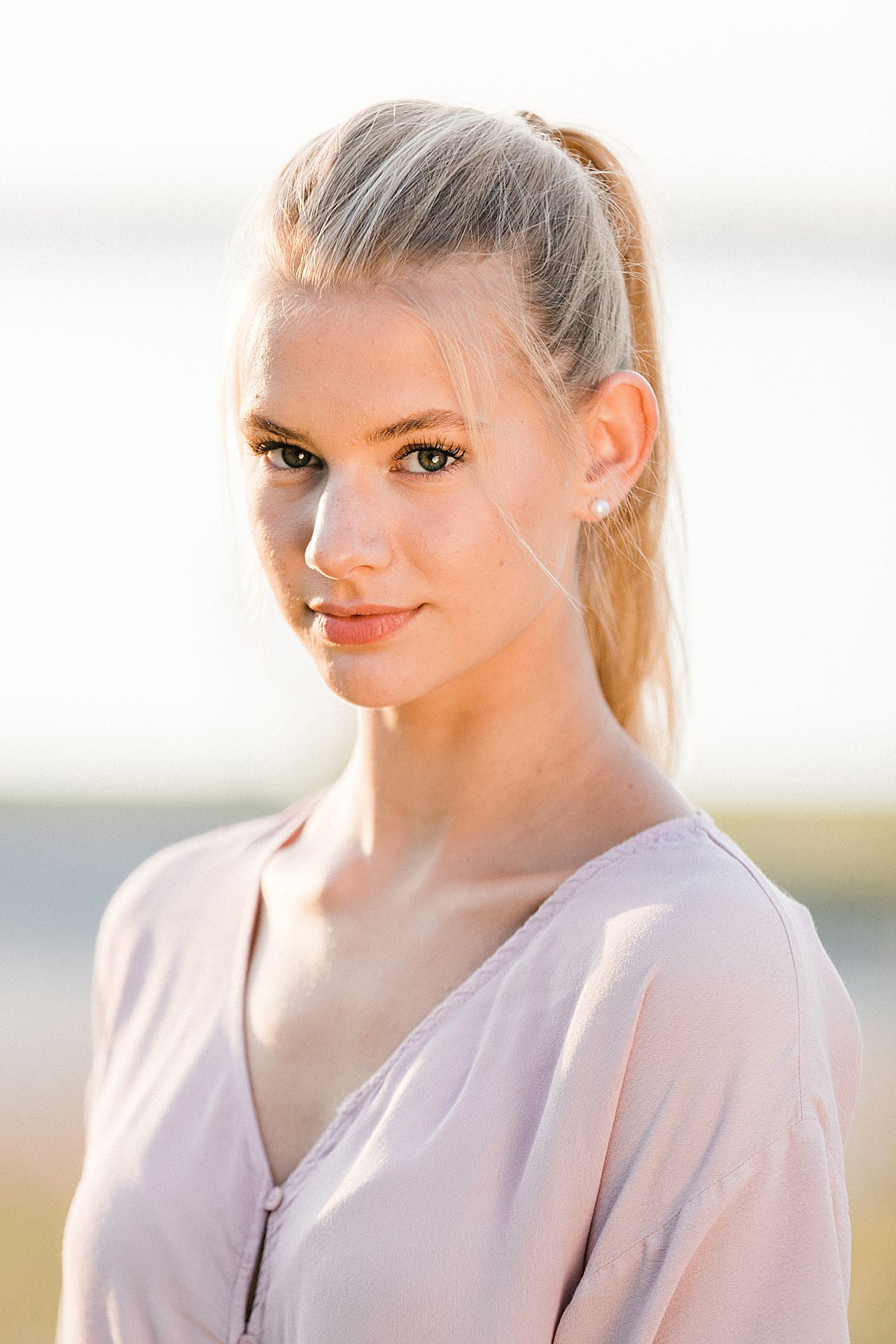 This is a photo of a high school senior girl looking directly into the camera at sunset in Northern Michigan