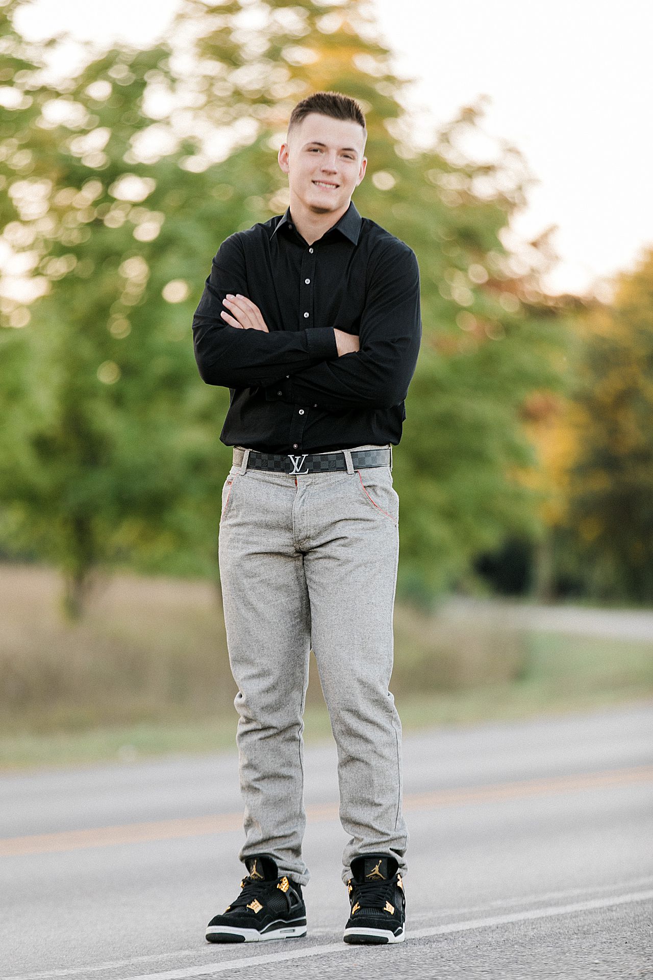 This is a male senior portrait smiling and standing with his arms crossed in Traverse City, Michigan