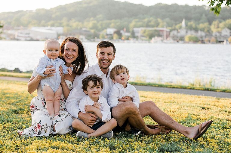 Parents smiling with their three young boys by the water