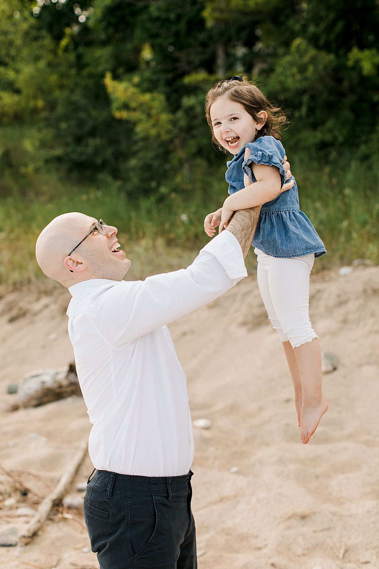 Dad lifting his young daughter in the air