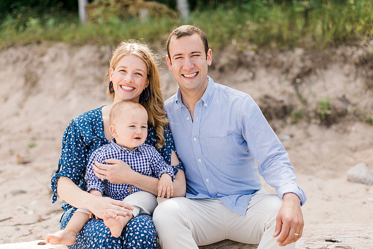 Father and mother sitting on a log at the beach with their son