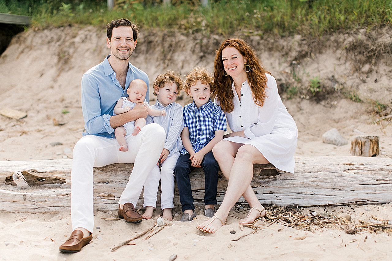 Family of five posing on a log on the beach in Northern Michigan