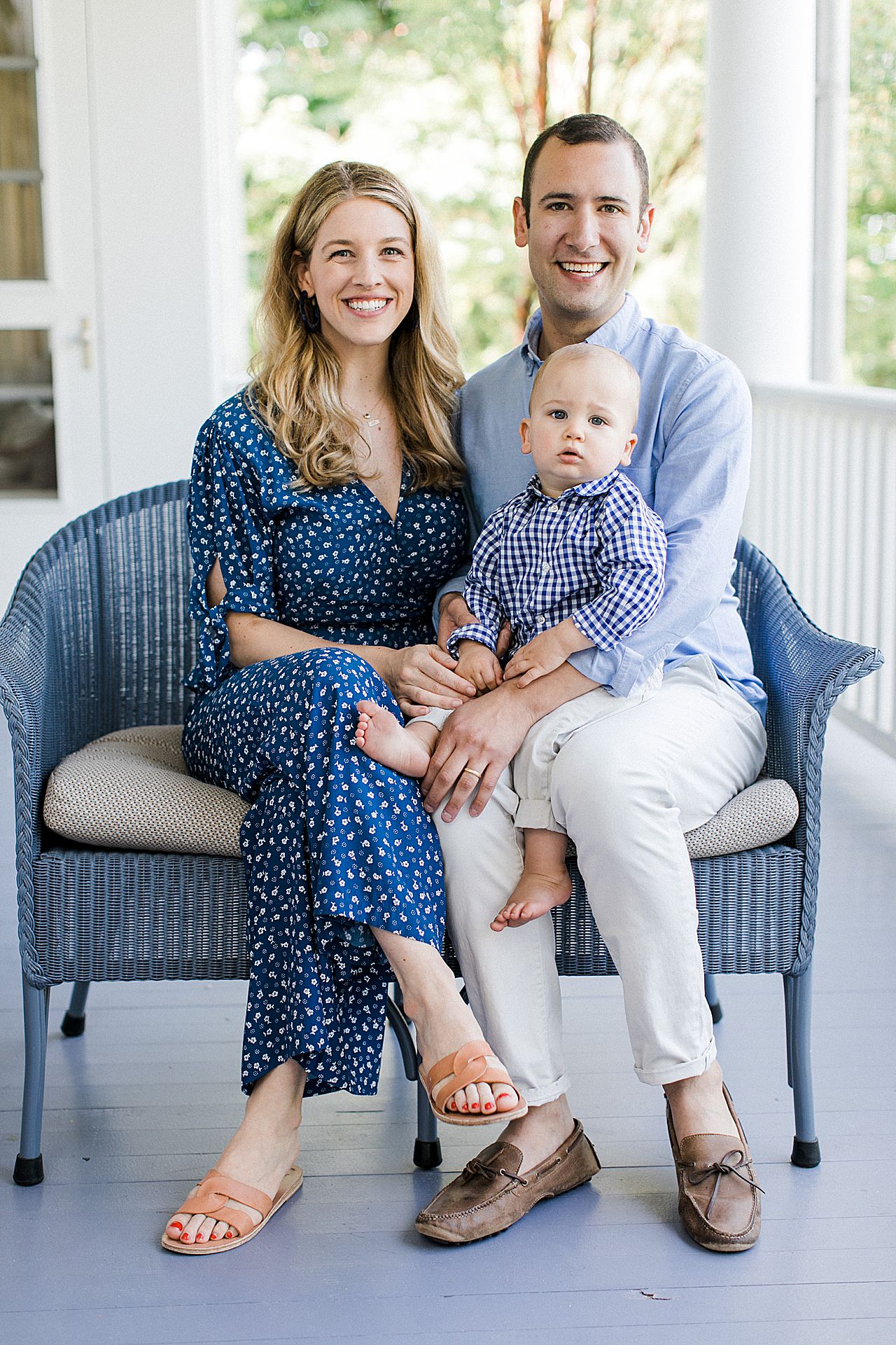Parents sitting on a porch with their young son in their laps
