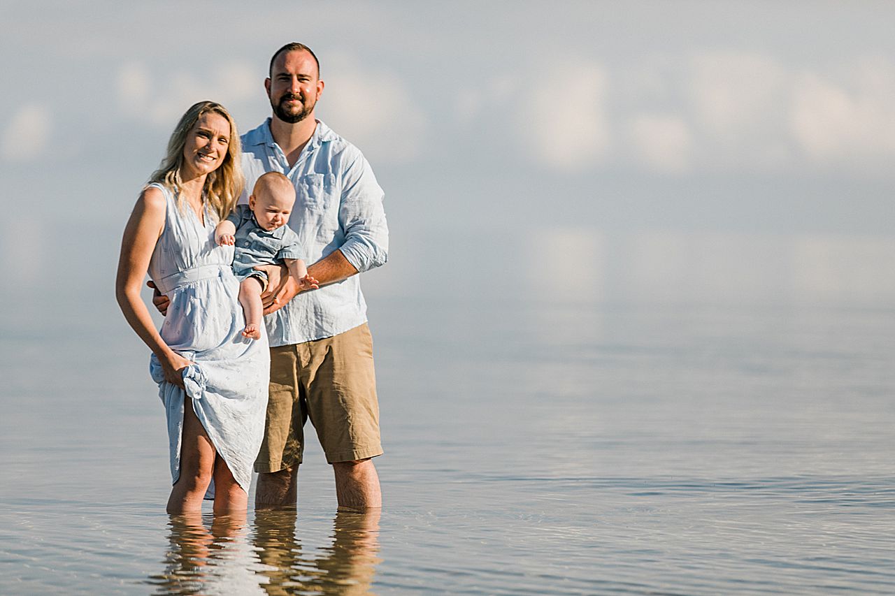 Young family holding their son and standing in the water in Northern Michigan