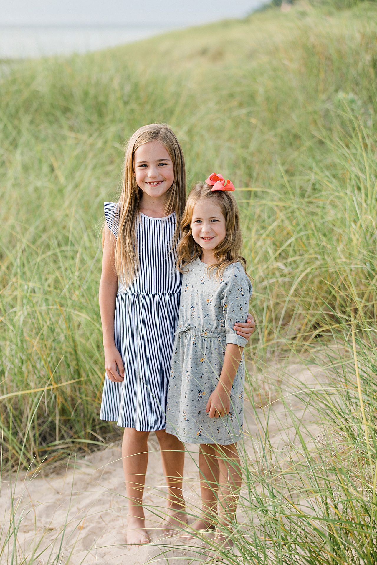Two young sisters hugging each other on a beach in Northern Michigan