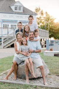 Grandparents sitting on a rock with all their grandkids