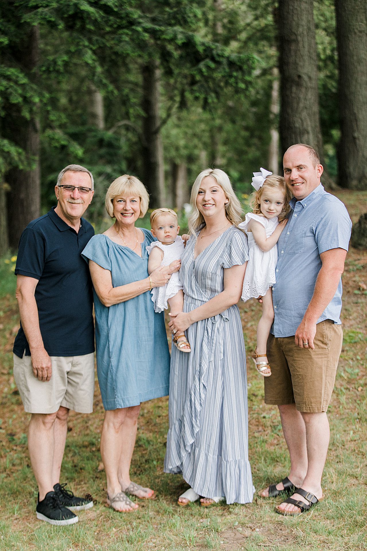 Grandparents, parents and kids posing for a portrait in a forest