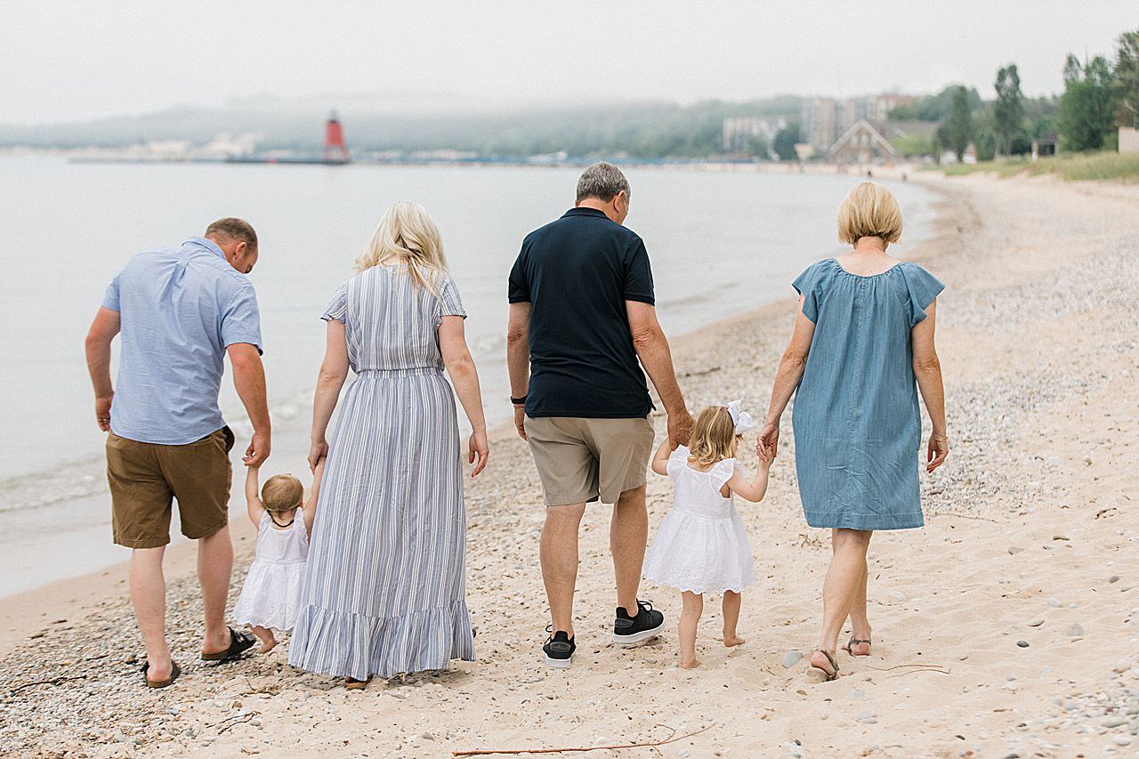 Grandparents, parents, and kids walking on a beach holding hands