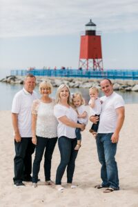 Family of six posing in front of a red lighthouse in Charlevoix, Michigan