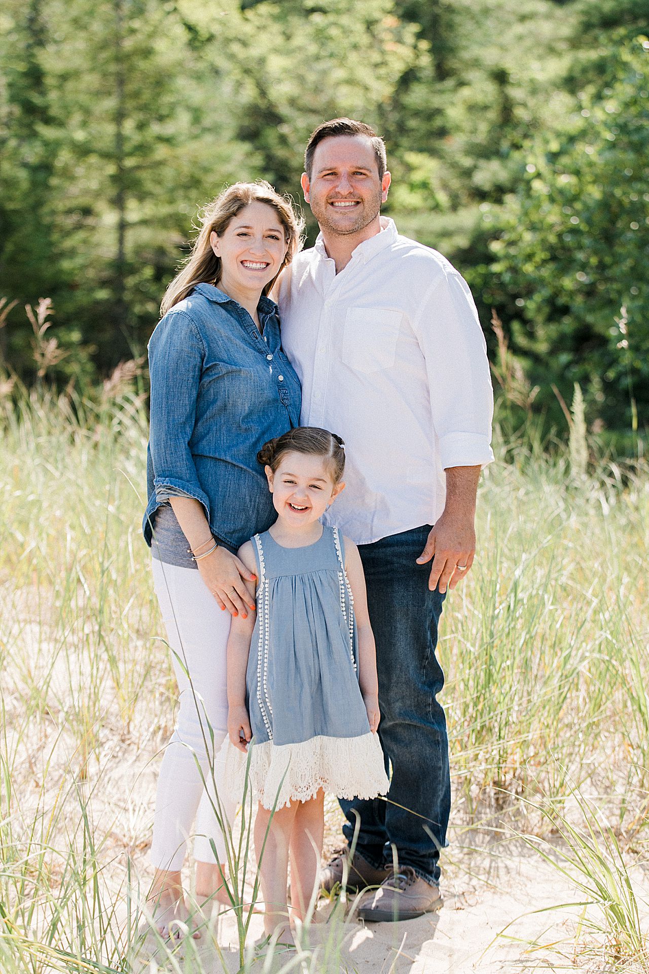 Mom and dad with their young daughter on a beach in Michigan