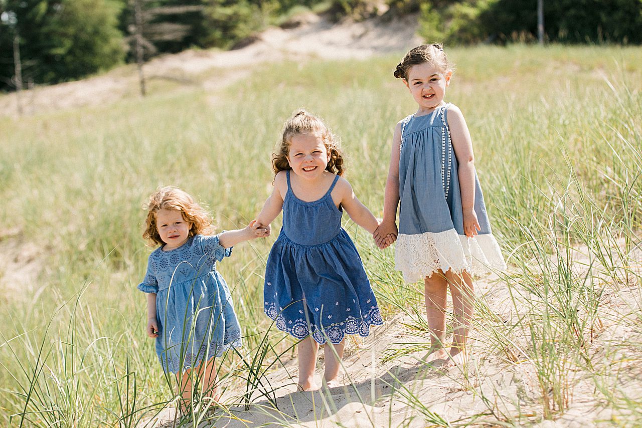 Three young girls holding hands on a beach in Northern Michigan