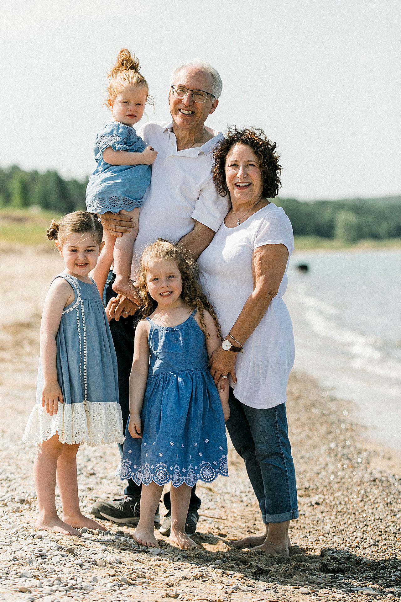 Grandparents holding their grandkids on a beach in Petoskey, Michigan
