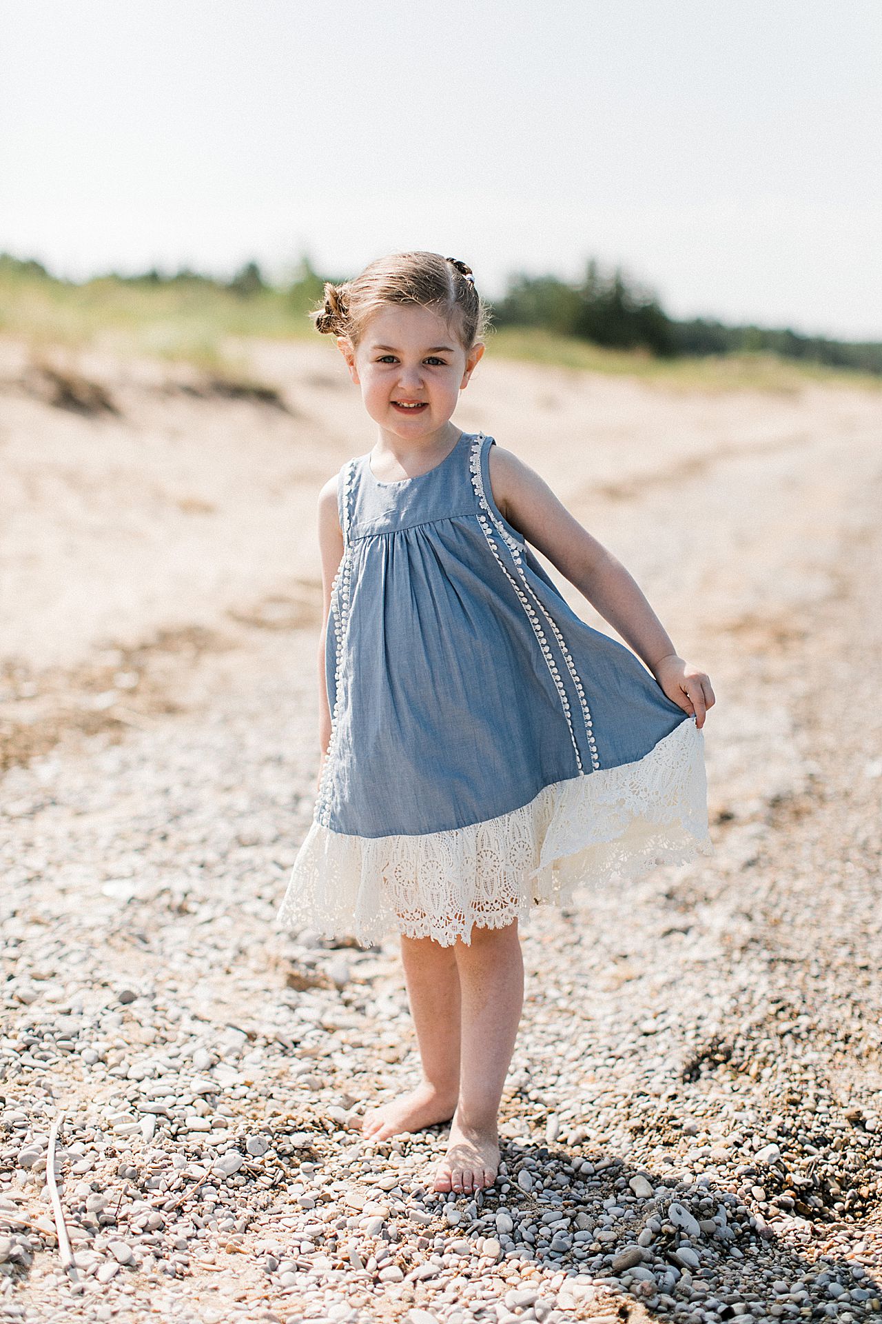A young girl showing off her dress on a beach in Petoskey, Michigan