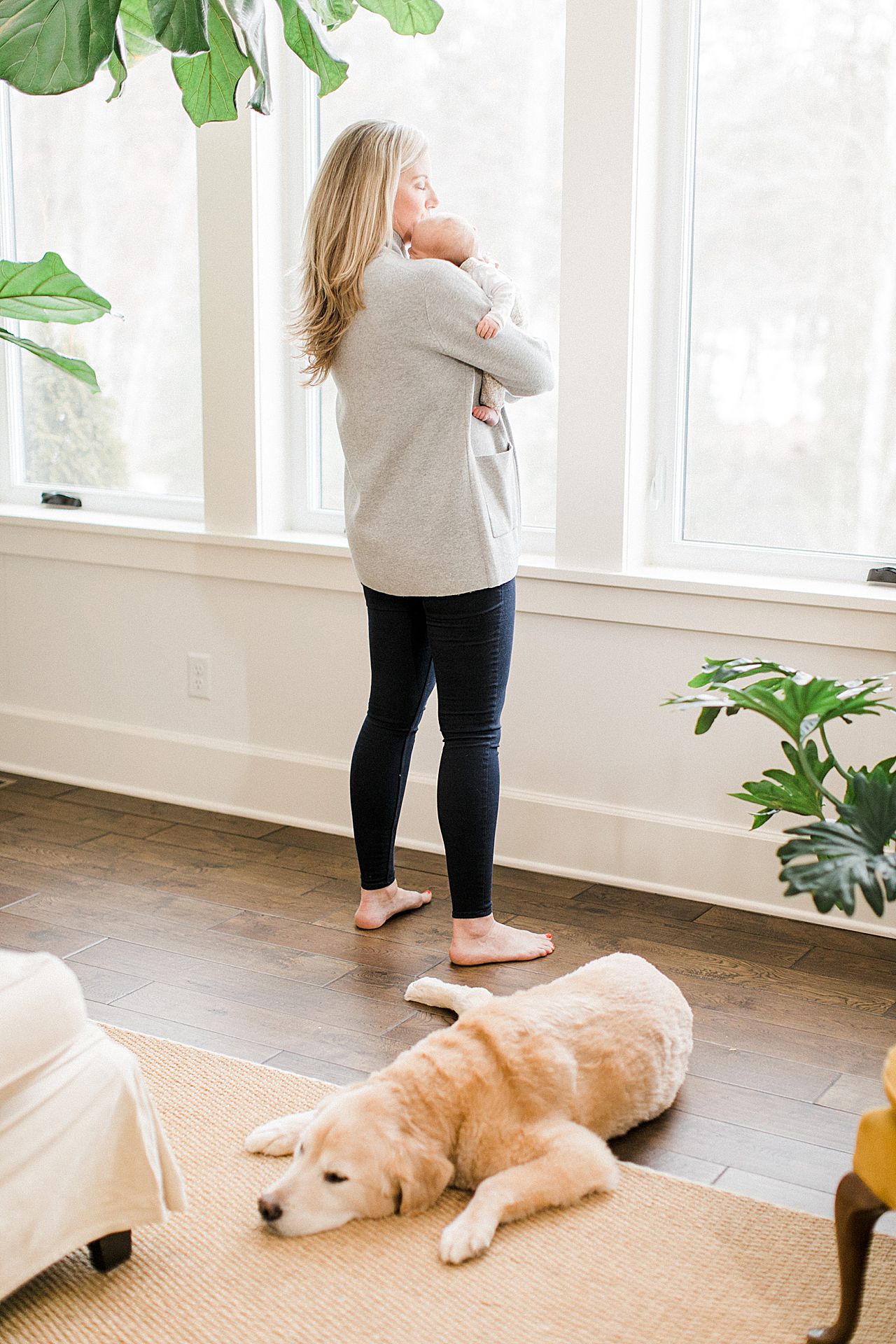 New mom holding her baby and looking out the window