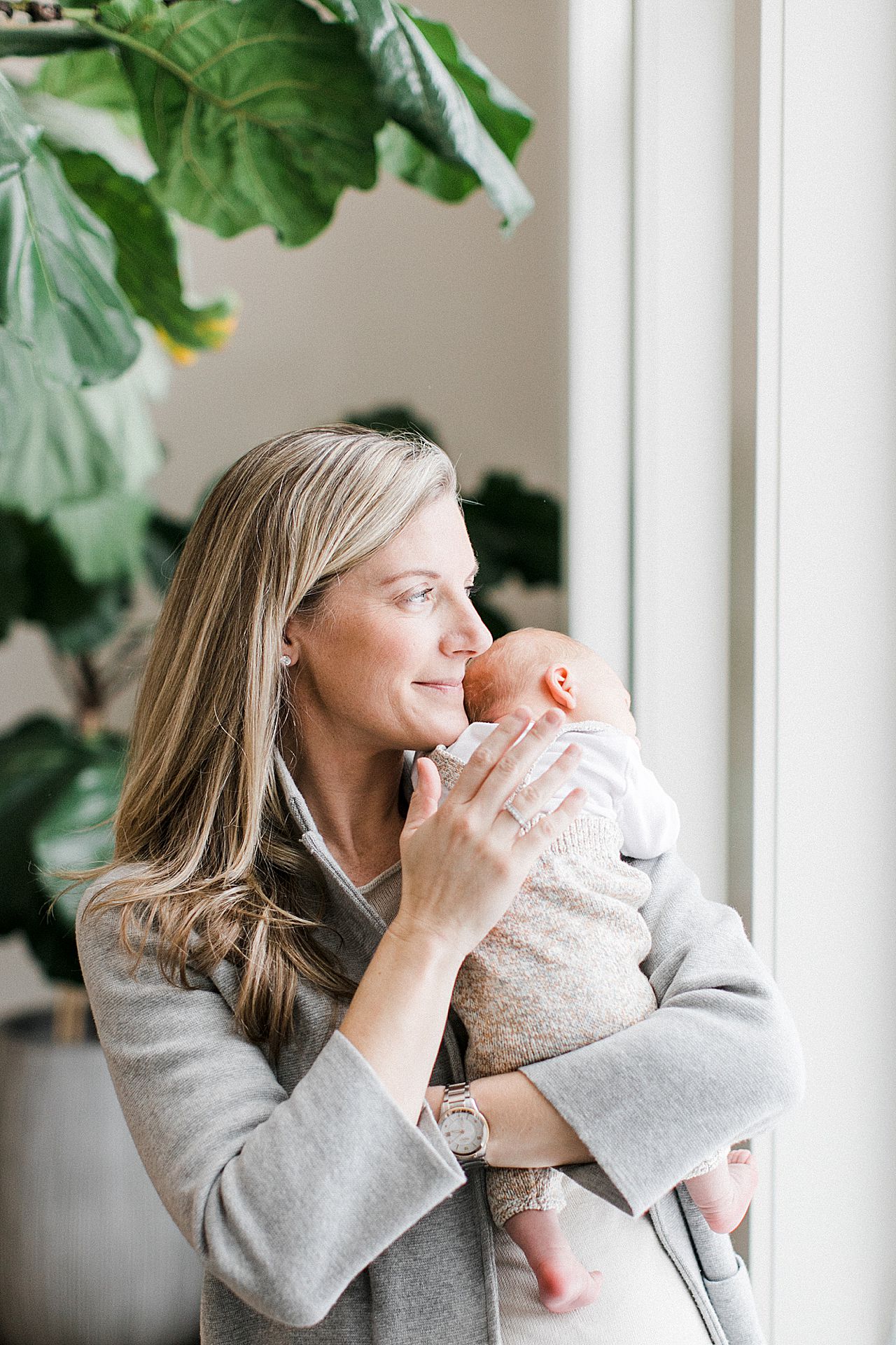 New mom holding her baby by the window