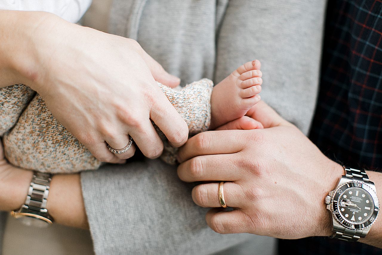 Close up details of newborn baby toes and the parent's hands