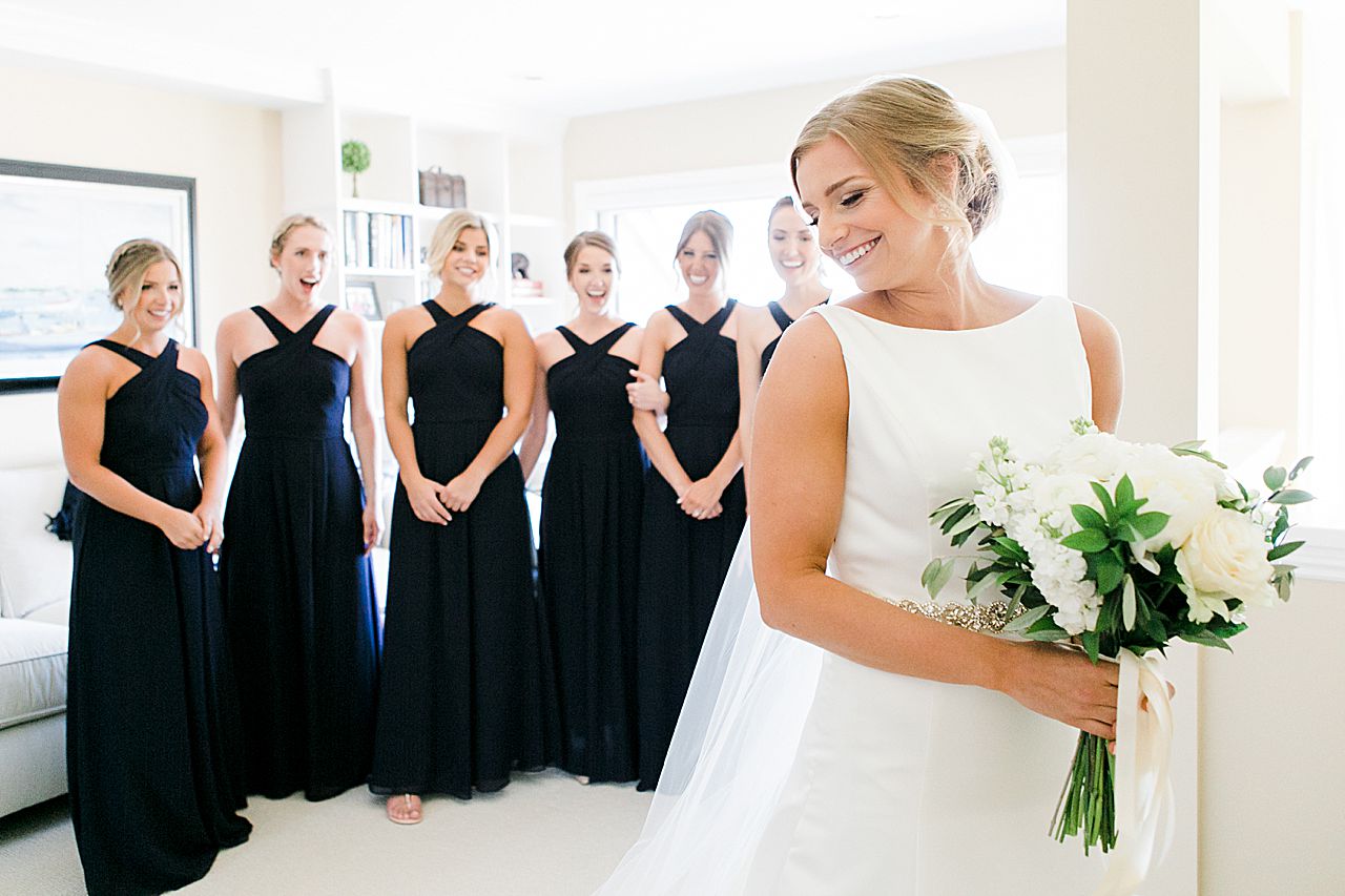 Bride walking into a room to show off her dress to her bridesmaids for the first time