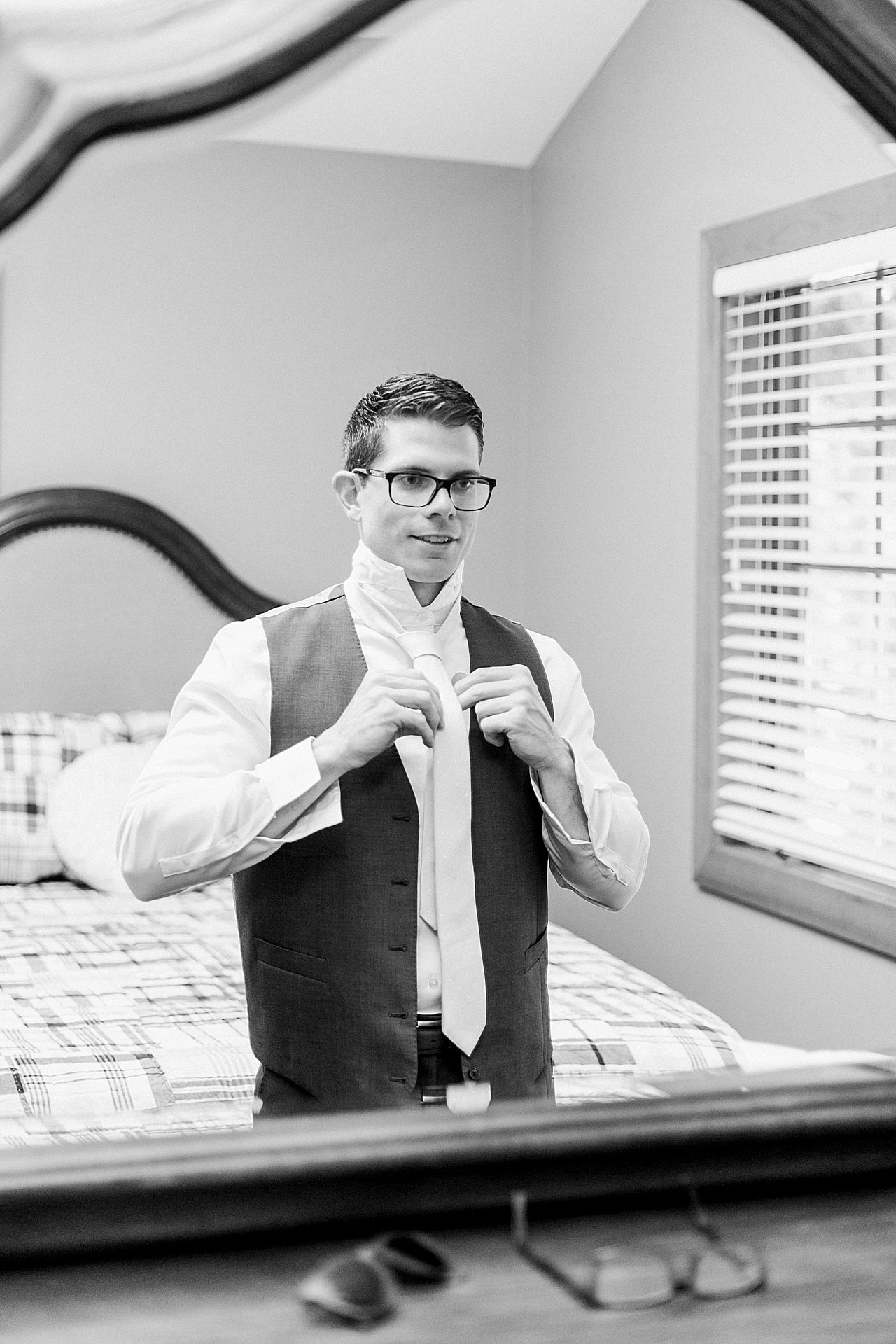Groom looking into a mirror putting on his tie