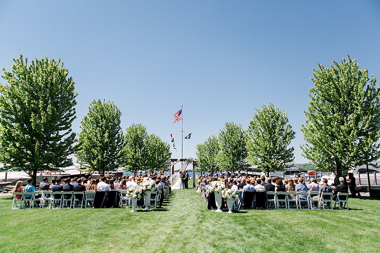 Wide photo of a wedding ceremony at The Harborage Marina in Boyne City, Michigan on a sunny day