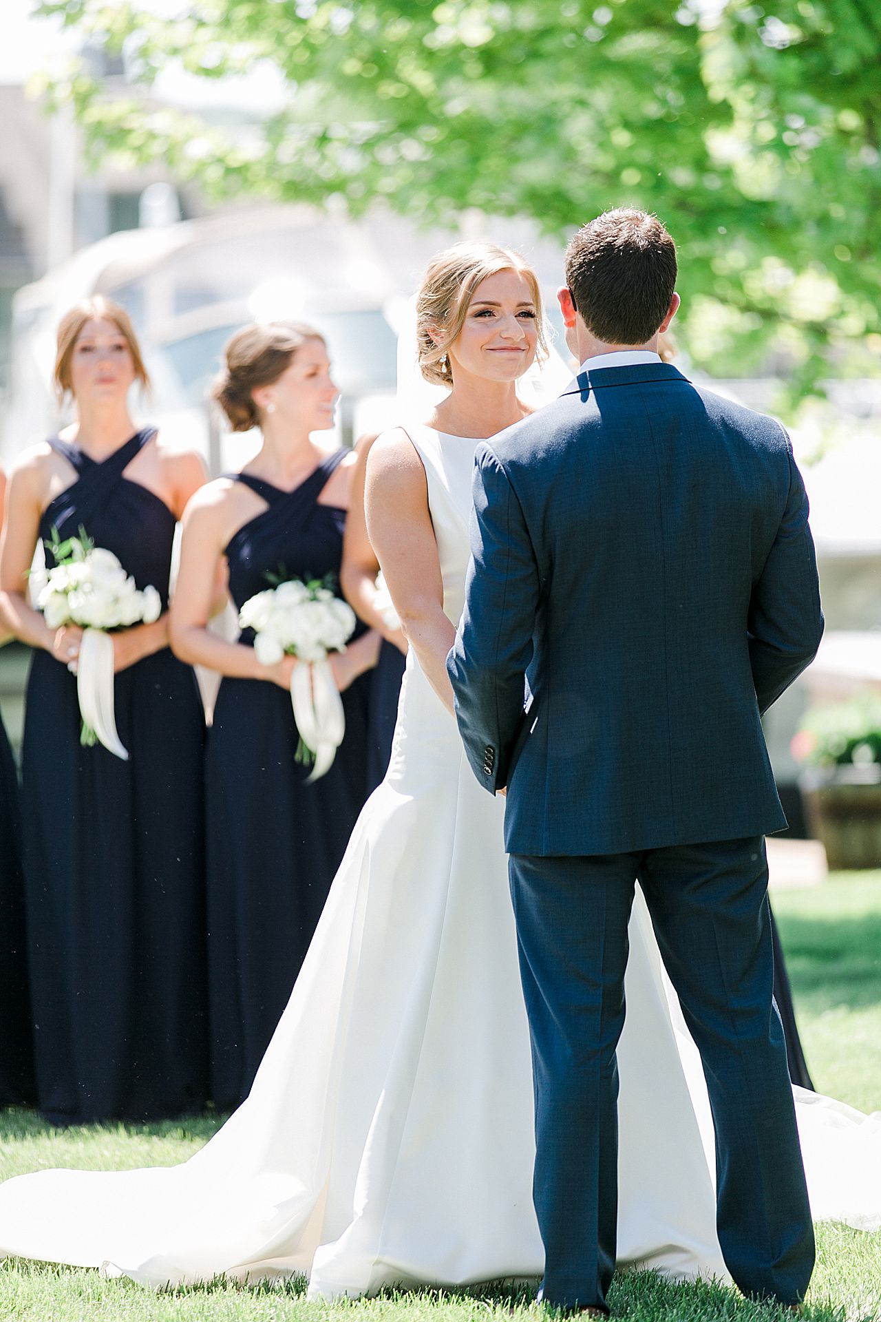 Close up image of a bride looking at her groom during their wedding ceremony on a sunny day at The Harborage Marina in Boyne City, Michigan