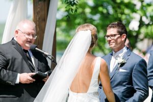 Close up image of a groom looking at his bride during their wedding ceremony on a sunny day in Boyne City, Michigan