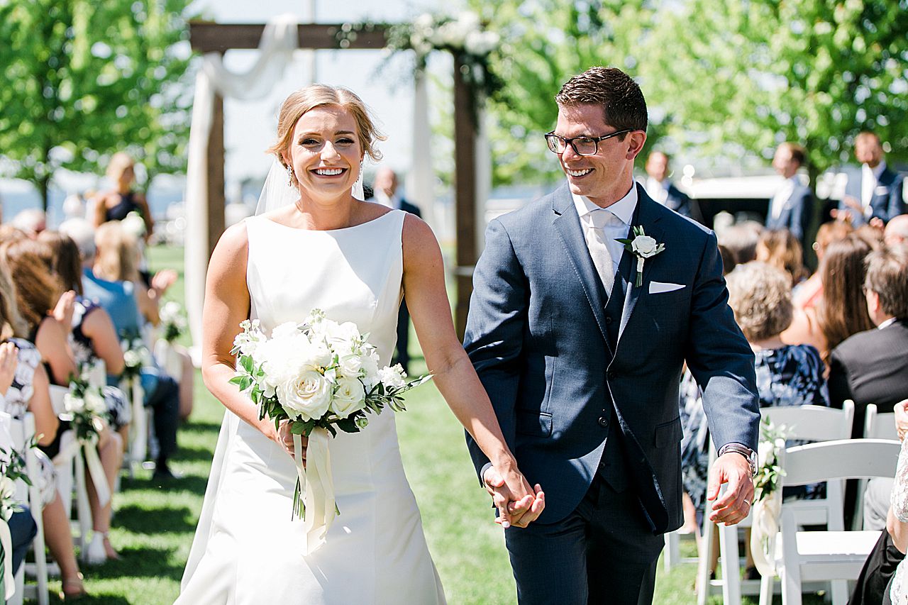 Bride and groom walking down the aisle together and holding hands after their first kiss