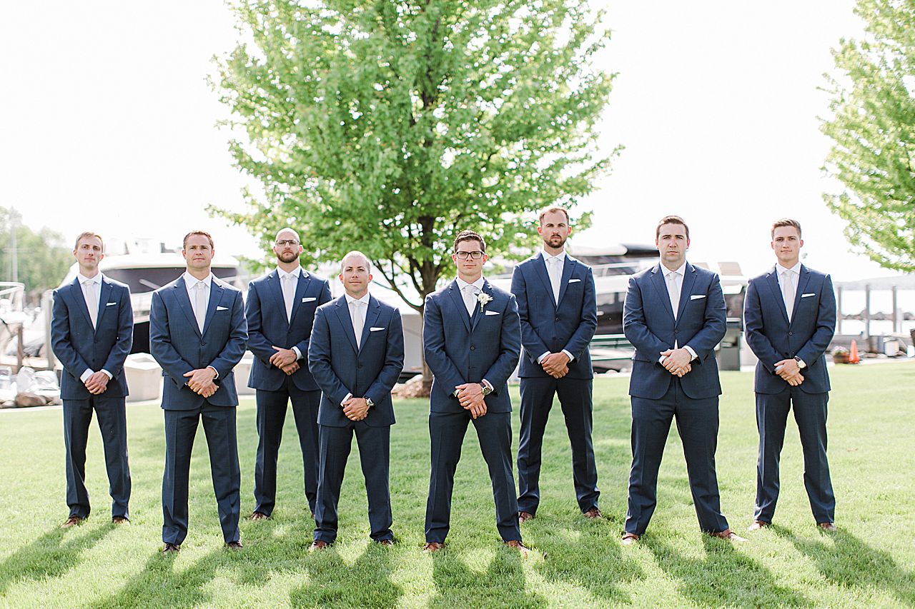 Groom and groomsmen in navy blue suits and brown shoes at The Harborage Marina in Boyne City, Michigan