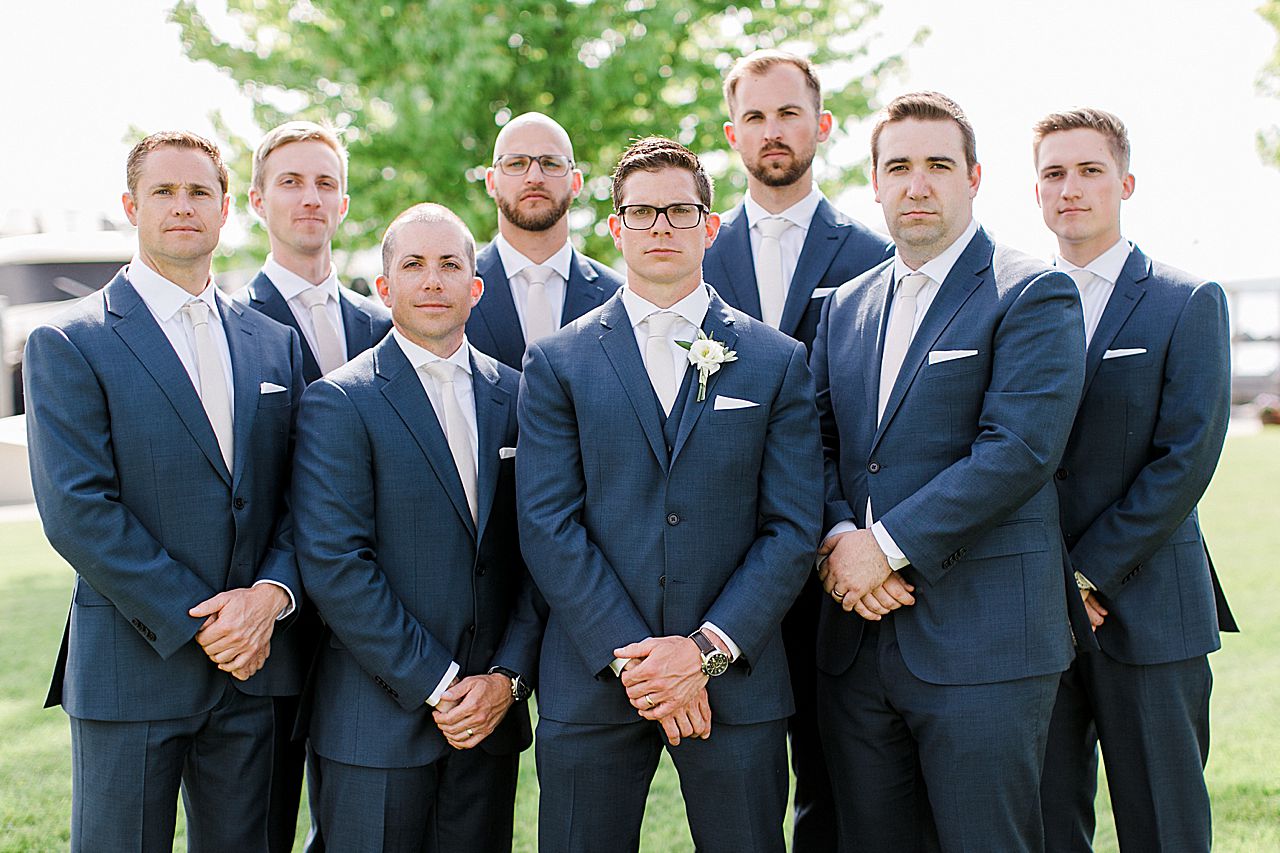 Groom and his groomsmen with their hands crossed in front of them with no smiles in Boyne City, Michigan