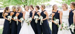 A bride and bridesmaids close together and laughing at each other at The Harborage Marina in Boyne City, Michigan