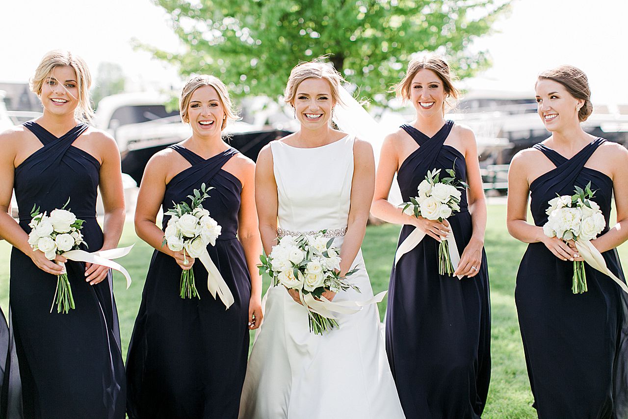 A bride smiling while she is walking towards the camera with her bridesmaids to her side