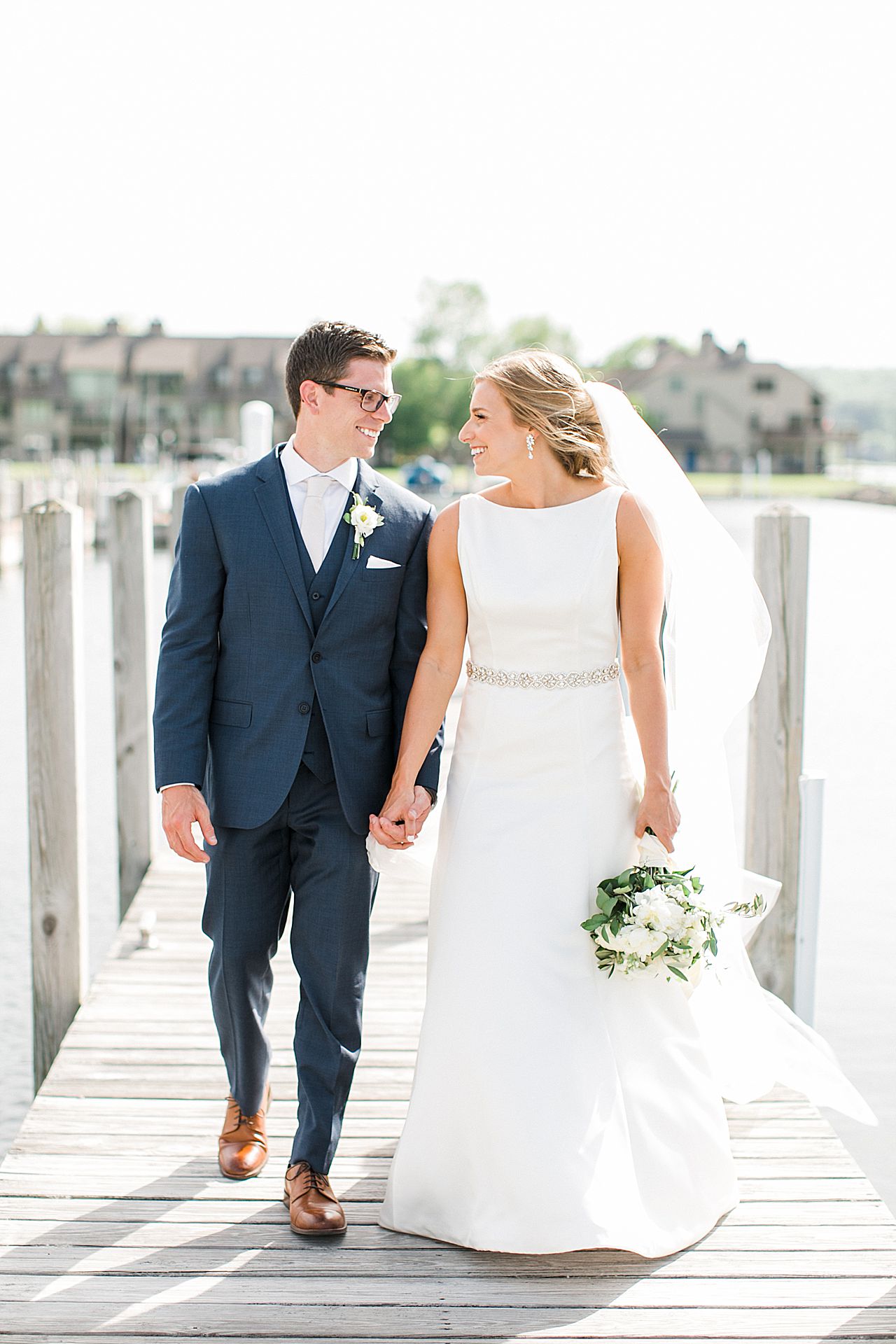 Bride and groom walking on a dock at a marina in Boyne City, Michigan