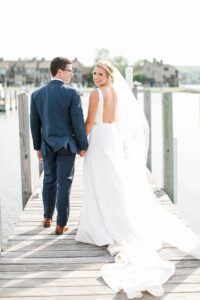 Bride holding the groom's hand and looking back at the camera while the groom looks at her in Boyne City, Michigan