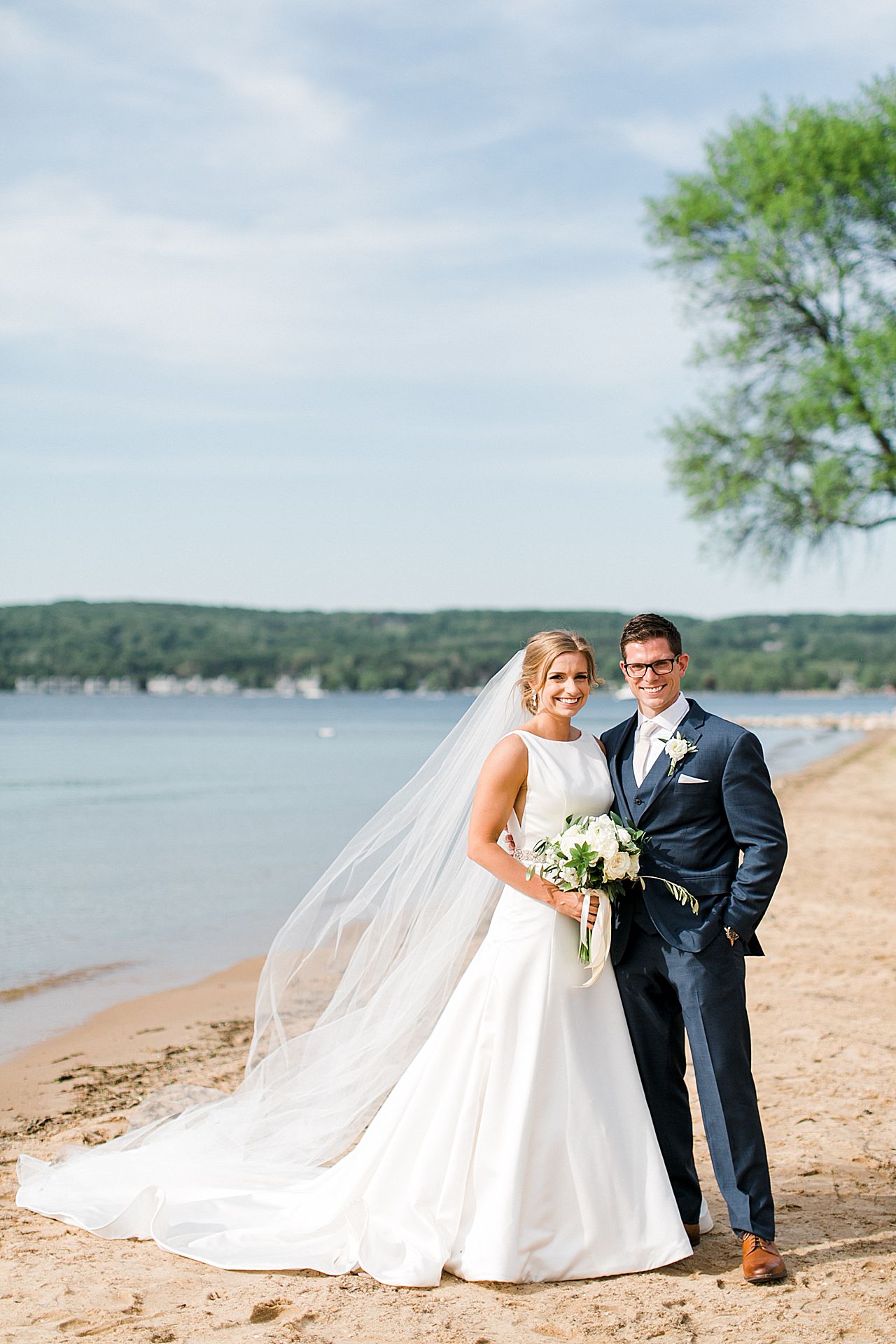 Classic, smiling bride and groom portrait at the beach on Lake Charlevoix in Boyne City, Michigan