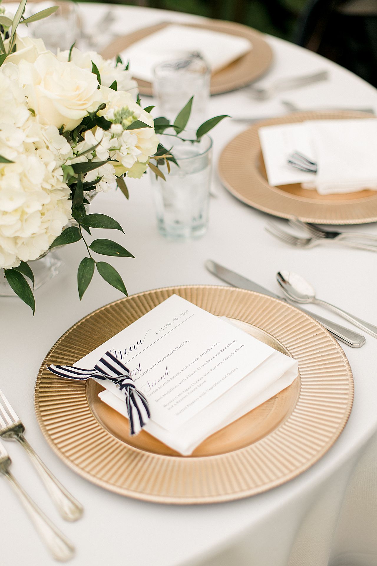 Gold chargers with a menu placed on top of the reception tables at Deer Lake at Boyne Mountain Resort in Boyne Falls, Michigan