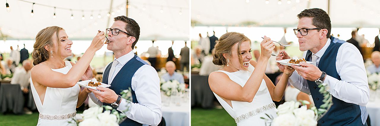 Bride and groom feeding each other cake in front of their guests at the wedding reception on Deer Lake in Boyne Falls, Michigan