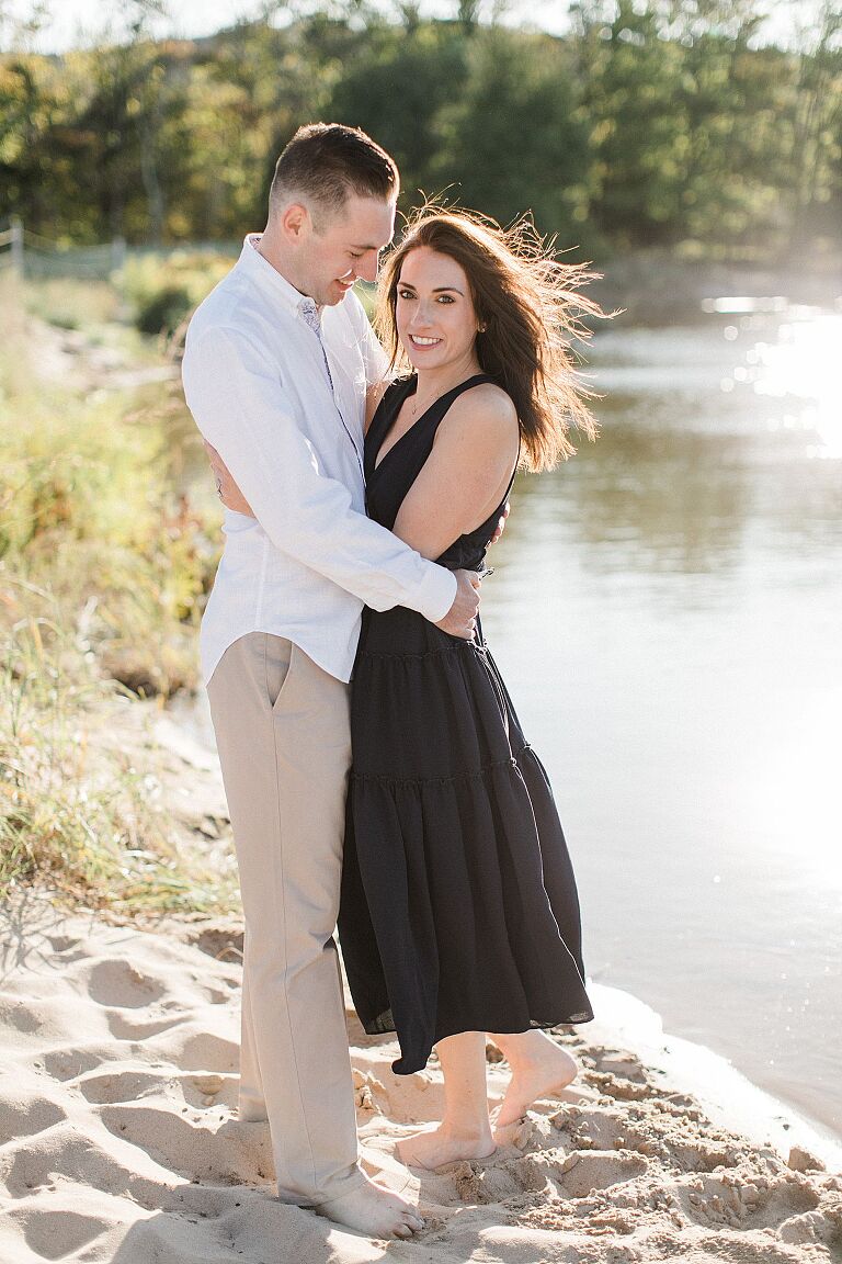 This is a couple taking engagement photos next to a lake in Empire, Michigan