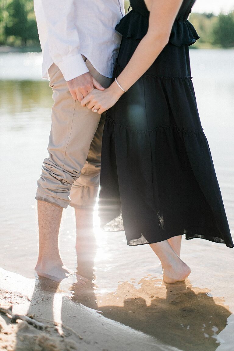 This is a couple holding hands while standing in the water in Empire, Michigan