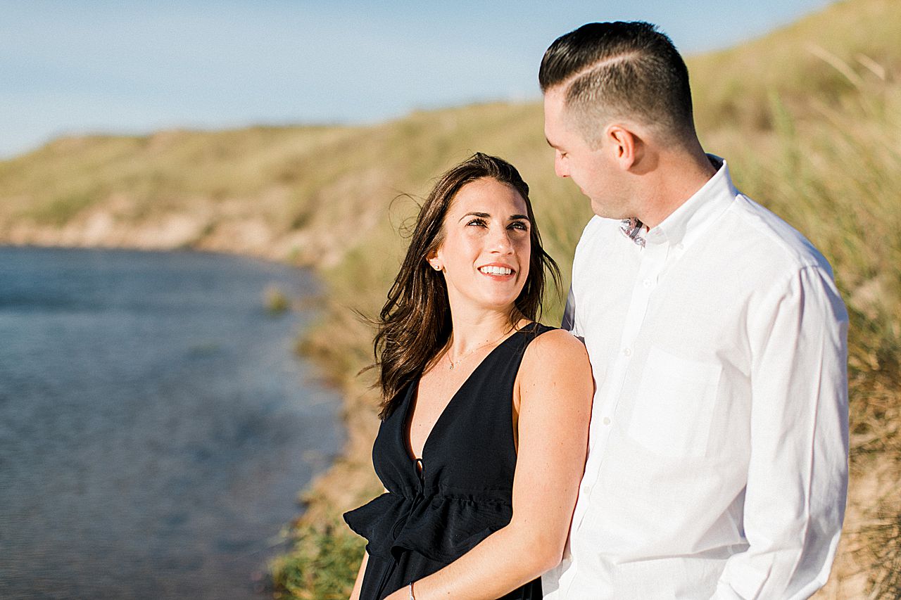 This is an engaged woman looking at her fiancé by a lake in Northern Michigan