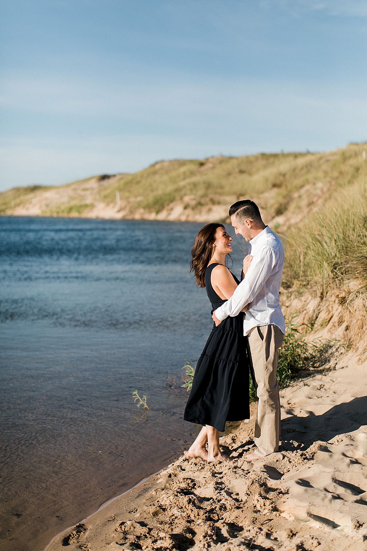 This is an engaged couple looking at each other by a lake in Empire