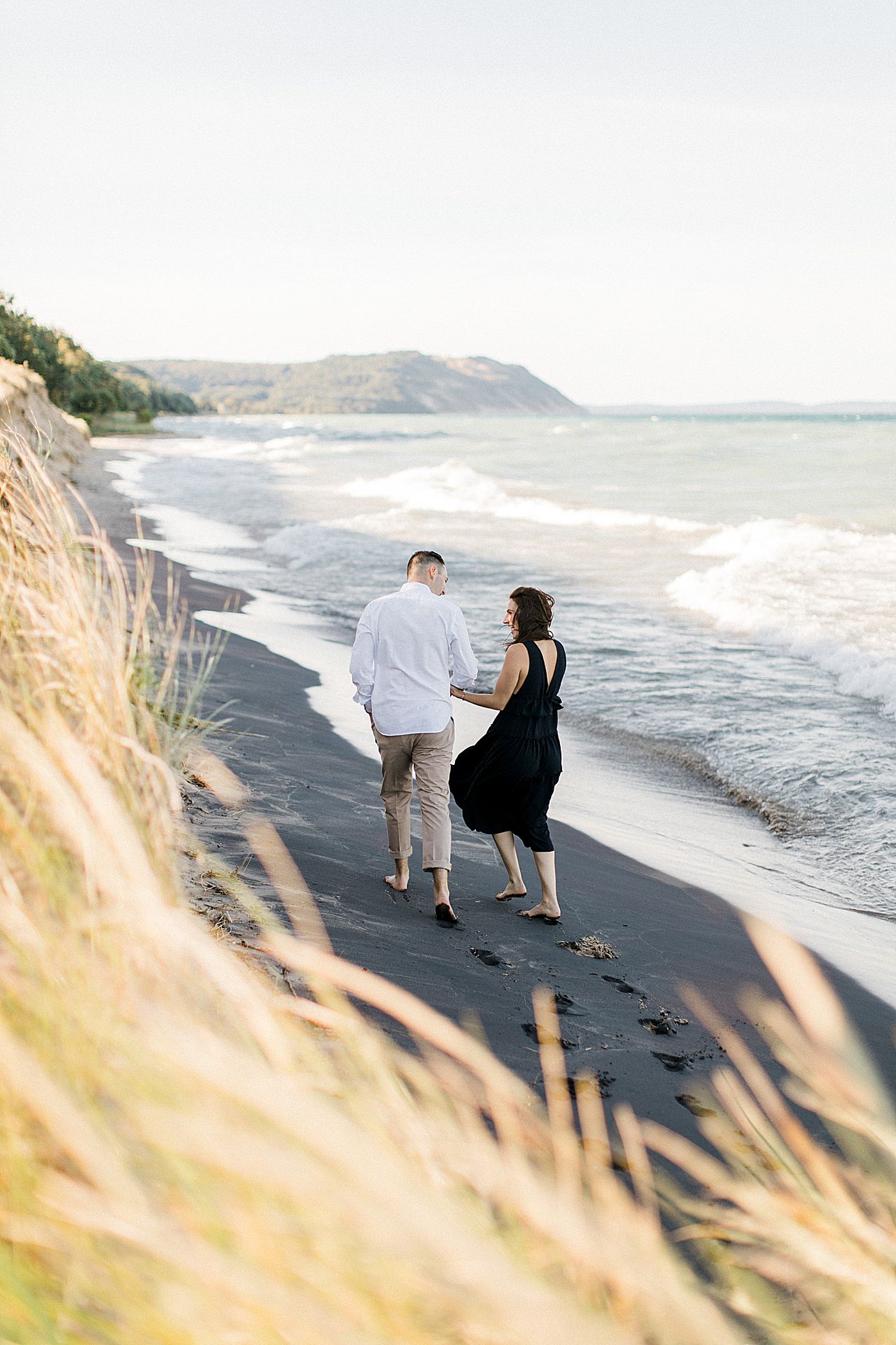 This is an engaged couple walking along Lake Michigan in Empire, Michigan