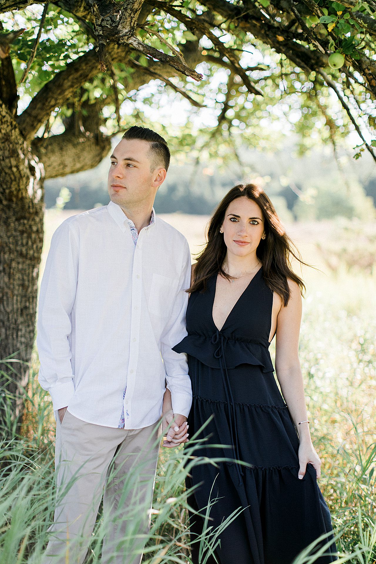 This is a portrait of a couple in a grassy field on a sunny day in Empire, Michigan