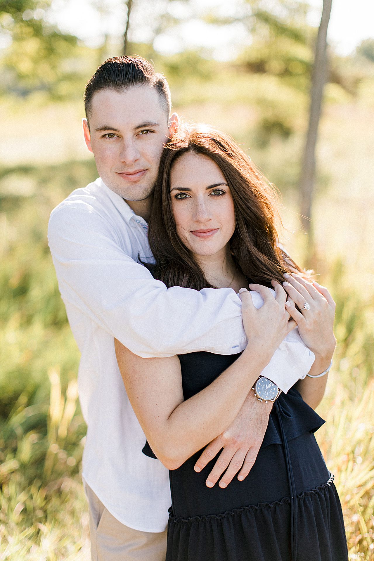 This is a portrait of man with his arms wrapped around his fiancé in Empire, Michigan