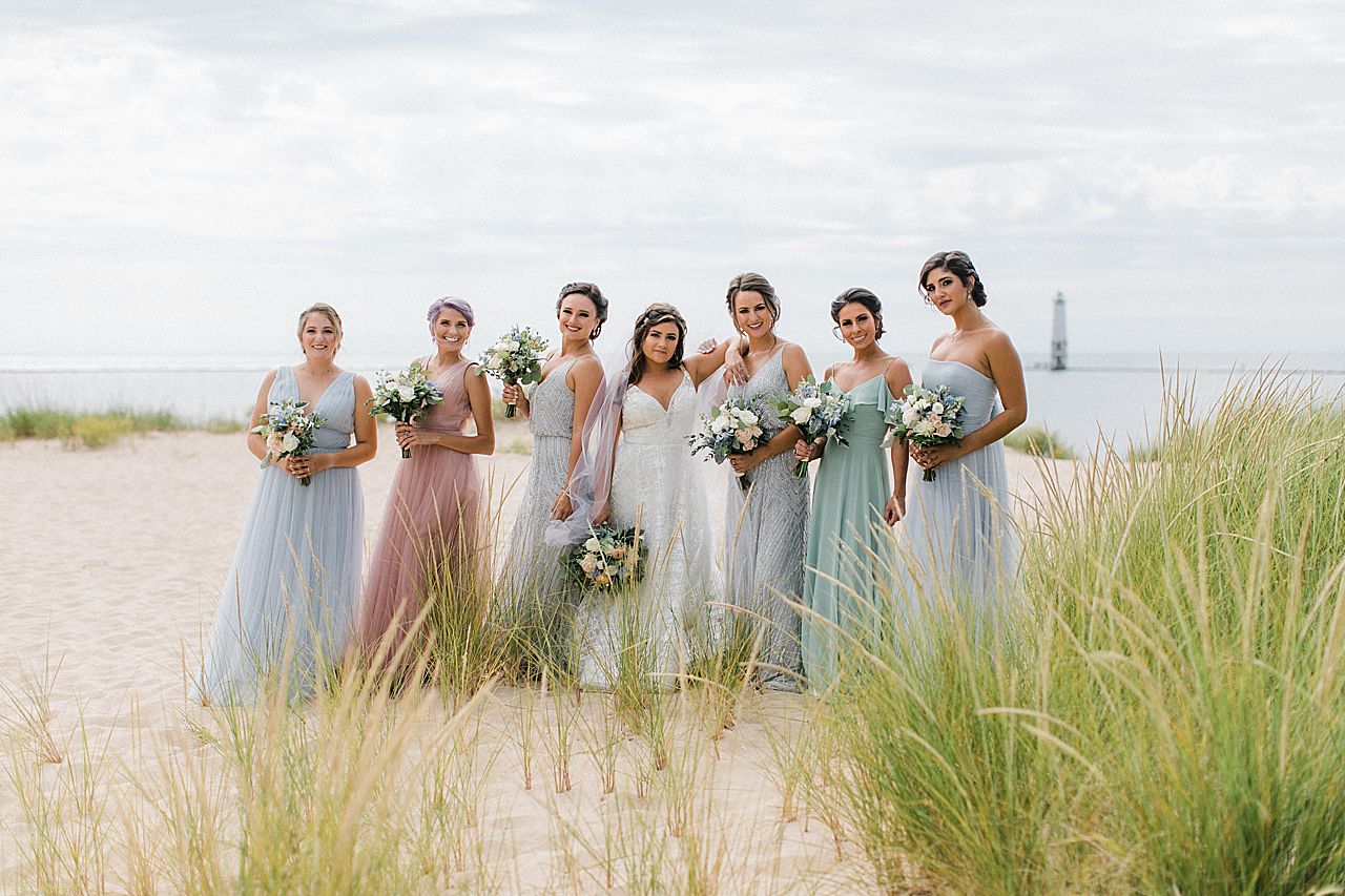 A bride with her bridesmaids by Lake Michigan with a lighthouse in the background