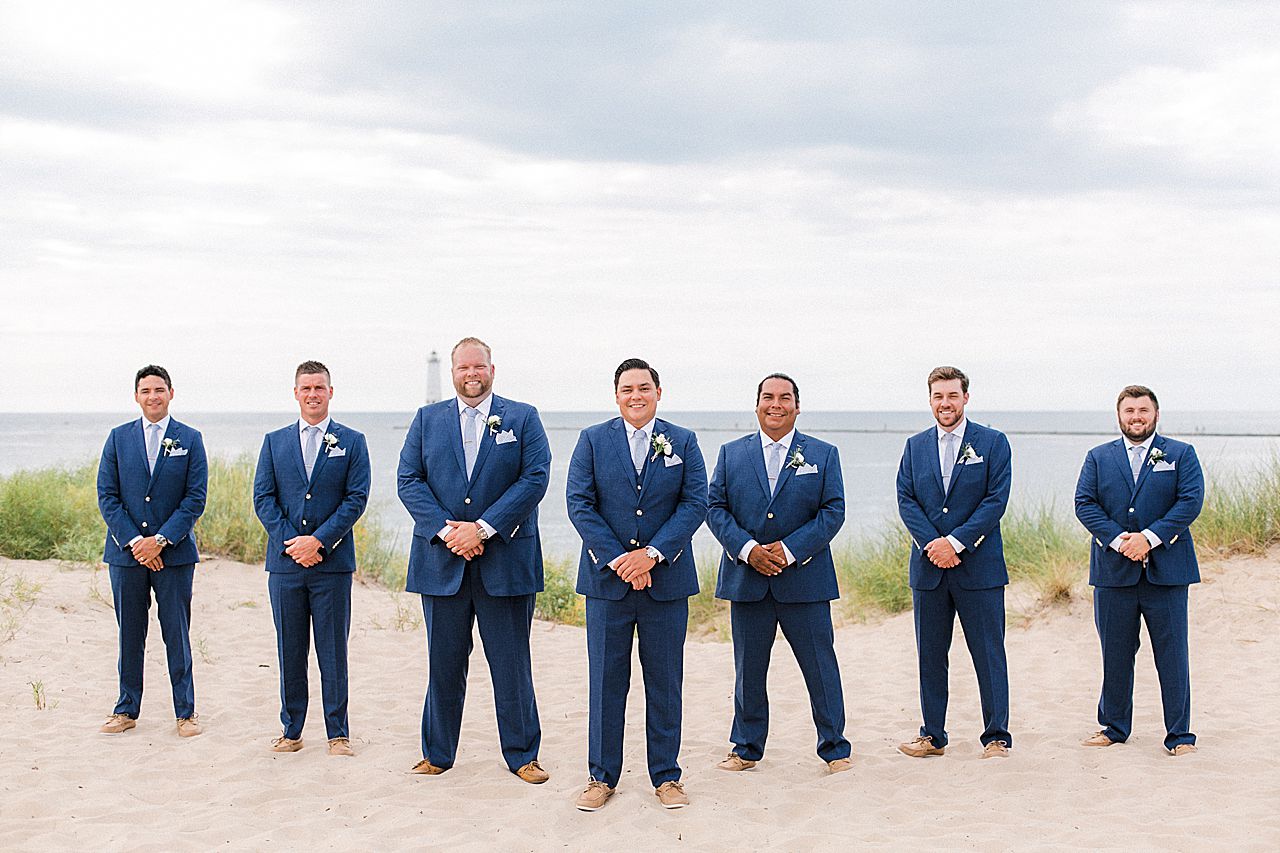A groom with his groomsmen on a beach in Frankfort, Michigan by Lake Michigan and a lighthouse