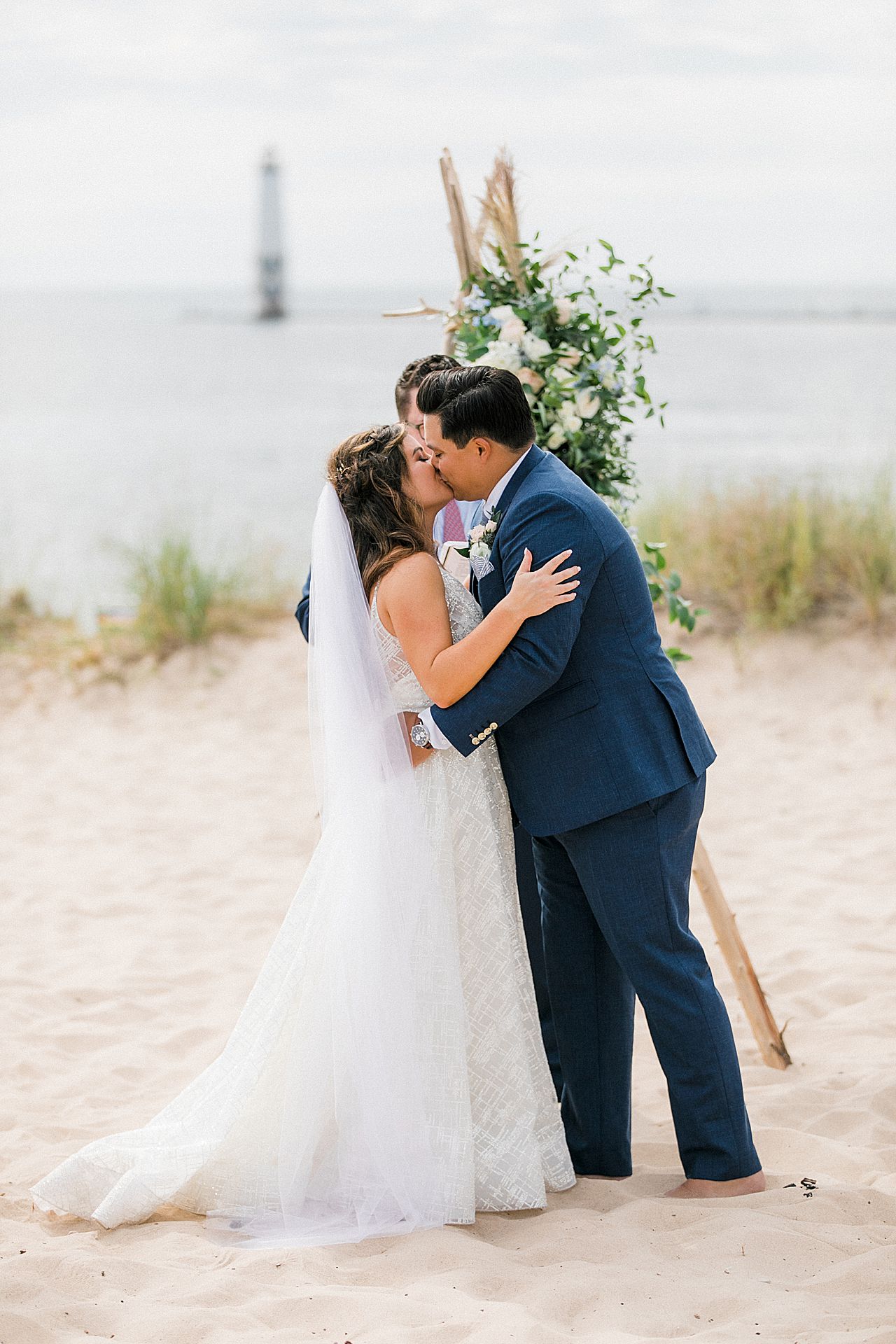 A bride and groom kissing at their wedding ceremony by Lake Michigan at Harbor Lights Resort in Frankfort, Michigan