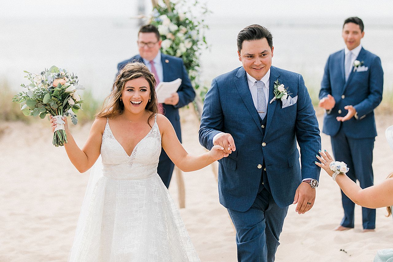 A bride and groom walking down the aisle at their wedding ceremony by Lake Michigan at Harbor Lights Resort in Frankfort, Michigan